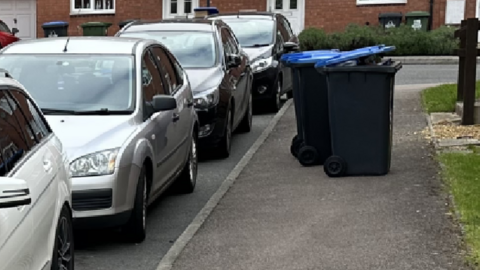 Parked cars next to bins