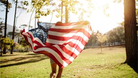 A young person runs with US flag