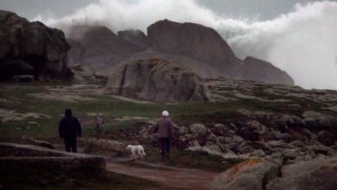 People watch waves breaking on the Brittany coast