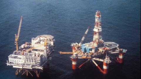 A floating platform next to a large oil rig