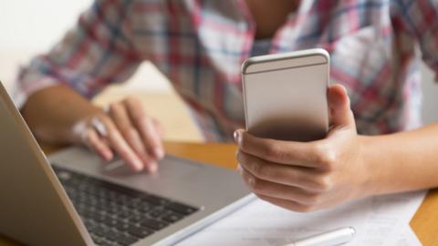 Stock photo of woman on phone and laptop