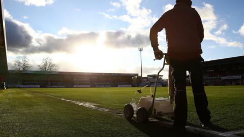 Ground staff paint the lines at Cheltenham Town