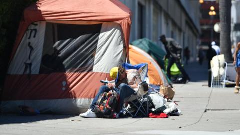 A homeless man sleeps in front of his tent along Van Ness Avenue in downtown San Francisco, California on June, 27, 2016.