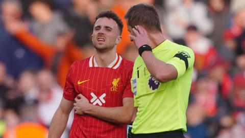 Liverpool forward Diogo Jota holds his side in pain