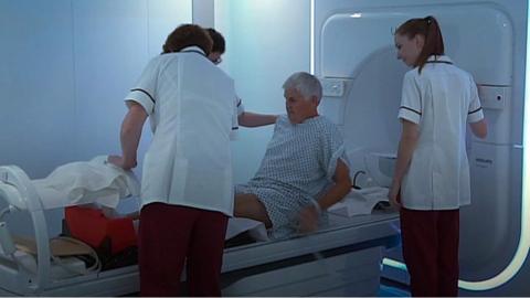 Patient and nurses standing near cancer machine