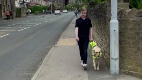 Louis walking down street with guide dog