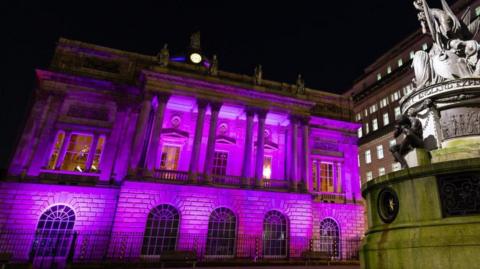 The front of Liverpool Town Hall is lit in purple