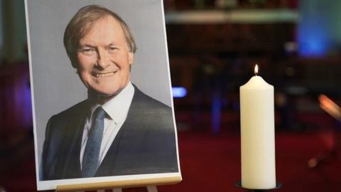 A candle and photo of Sir David Amess at church in Leigh-on-Sea