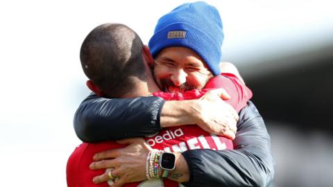 Eoghan O'Connell is hugged by Wrexham co-owner Ryan Reynolds