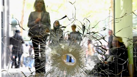 People look at a bullet hole in a window near to the Marks and Spencer on the Champs Elysees in Paris following the shooting of a police officer, 21 April