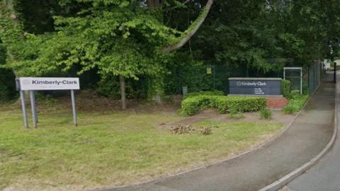 Sign of Kimberly-Clark factory on a grass verge near the entrance of the factory 