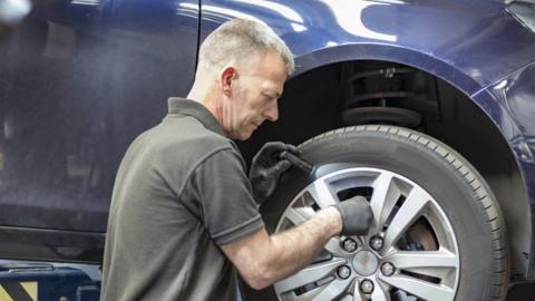 Mechanic tests brakes at a car service centre.