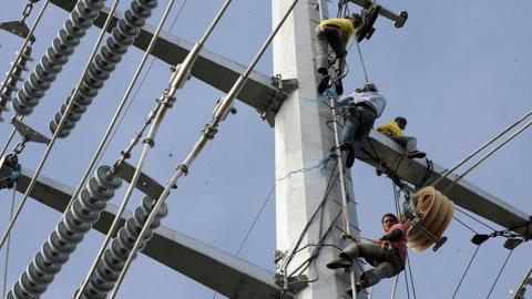 Linemen install cables on the Transco power transmission line in Santa Rosa town south of Manila on January 15, 2009