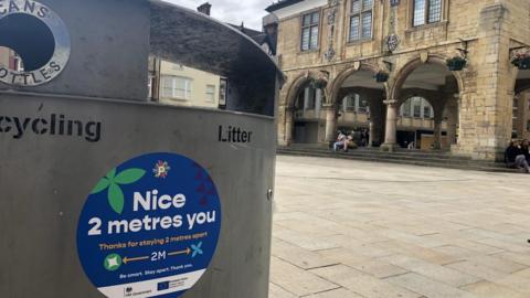 A sign reminding people to social distance on a bin in Peterborough