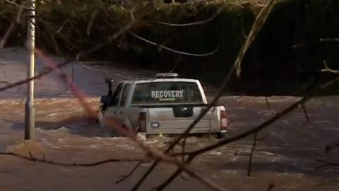 4 x 4 truck with 'recovery' markings in rear windscreen floats on flooded road