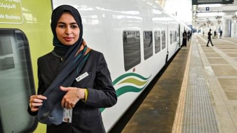 An employee stands outside a train at the airport station in Jeddah