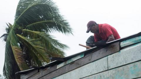 A man prepares his roof as a powerful hurricane approaches