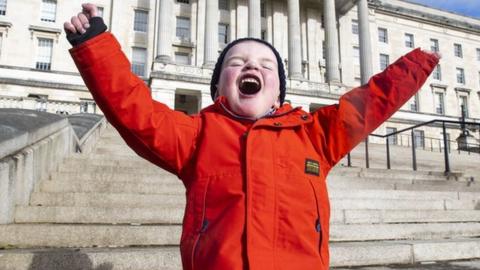 Dáithí Mac Gabhann celebrates on the steps of Stormont after the organ donation bill was passed