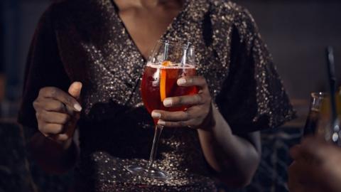 Stock image of a woman in a sparkly top holding a drink