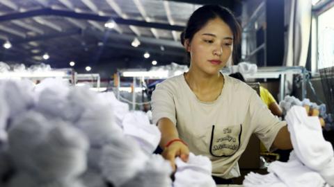 A woman works on socks that will be exported to the US at a factory in Huaibei in China's eastern Anhui province on August 7, 2018