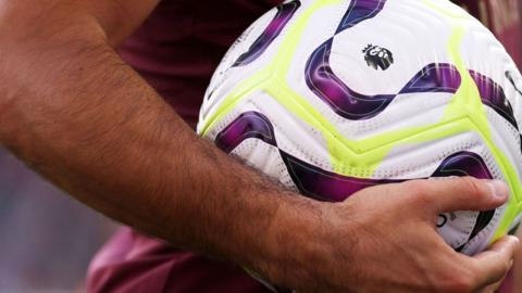 A Premier League ball being held by a player