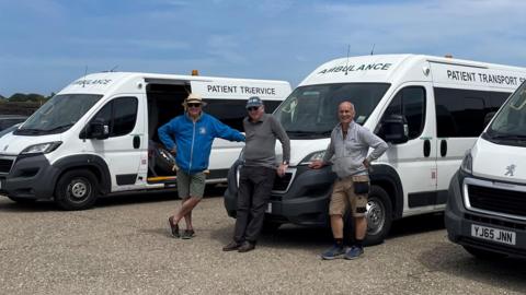 John Nickell-Lean (middle) in front of three ambulances