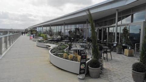 An upper level outdoor walkway beside restaurants at the Westgate shopping centre