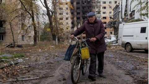 A man walks with bicycle in front of damaged residential buildings in Avdiivka, eastern Ukraine. File photo