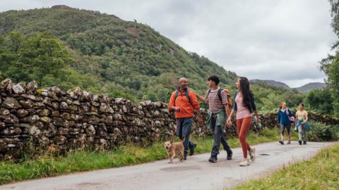 people walking with a dog along a country lane.