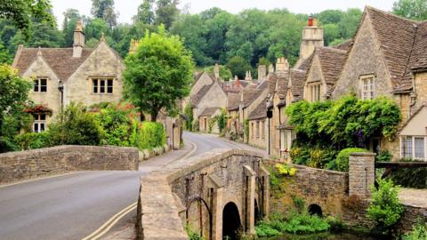 The centre of the village of Castle Combe in the Cotswolds showing traditional houses next to a stone bridge