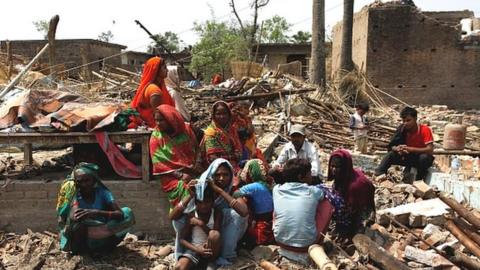 People sit on rubble left by a storm in Bara district, Nepal April 1, 2019