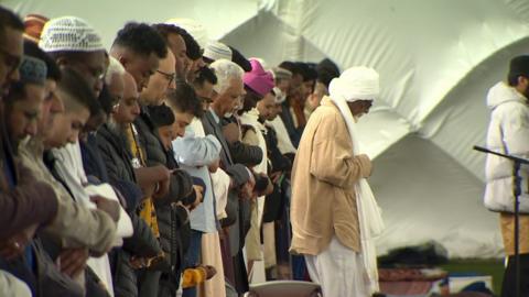 Muslims bow their heads in prayer at a Belfast event to celebrate Eid