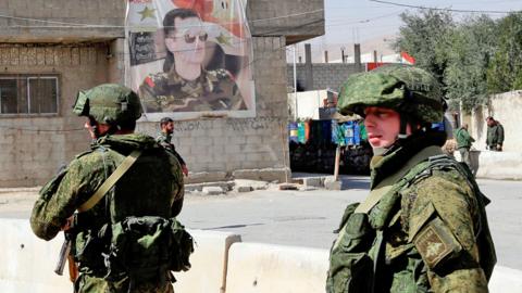 Russian military police members stand guard at the Wafideen checkpoint on the outskirts of the Syrian capital Damascus