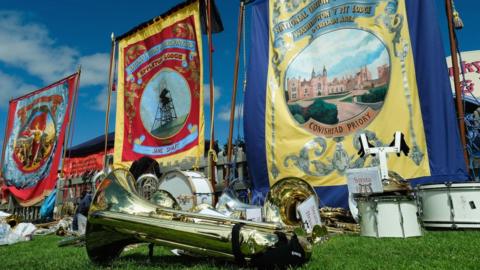 Library image of a trumpet on the grass with three gala banners in the background