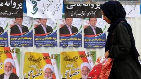 Iranian woman walks past election campaign posters in Tehran (19/02/20)