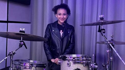 Nandi Bushell standing behind a drum kit