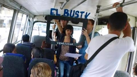 Woman holds a cardboard box reading El Bus TV