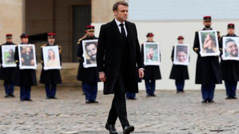 President Macron walks as photographs of the 42 French nationals killed in the Hamas attacks are held by the French Republican Guards