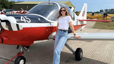 Katherine Moloney leaning against the wing of a Bulldog aircraft