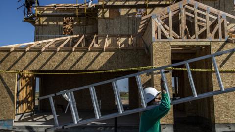 A worker carries a ladder into a home under construction at the planned community at River Islands in Lathrop, California Thursday, Mar. 4, 2021.