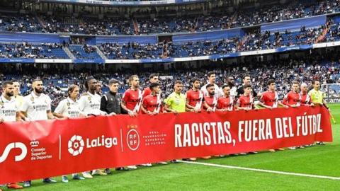 Real Madrid and Rayo Vallecano players hold a banner saying "racists out of football" in support of Vinicius Jr before last Wednesday's La Liga match at the Bernabeu