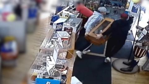 CCTV image of two men stealing a cabinet of mobile phones