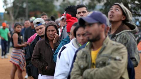 Migrants, part of a caravan heading to the US, queue for aid in Tijuana, Mexico, on 19 November 2018