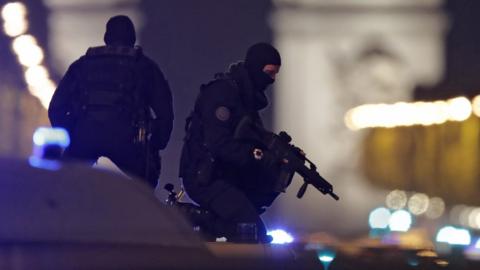 Masked police stand on top of their vehicle on the Champs Elysees Avenue after a policeman was killed and another wounded in a shooting in Paris, 20 April 2017