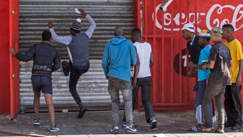 South African looters try to break into an alleged foreign-owned shop during a riot in Johannesburg