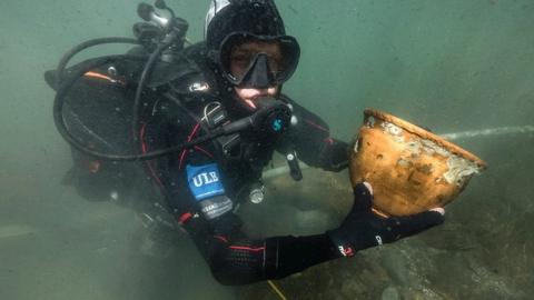 A diver shows one the vases found in Lake Titicaca