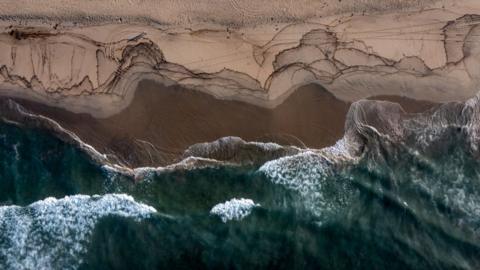 An aerial view of a major oil spill washing ashore