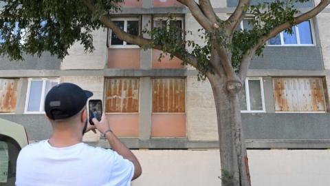 A man takes pictures of the building in Marseille where a woman was shot inside her flat