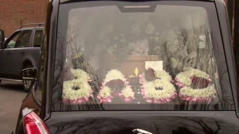 Funeral car with flower tribute on display