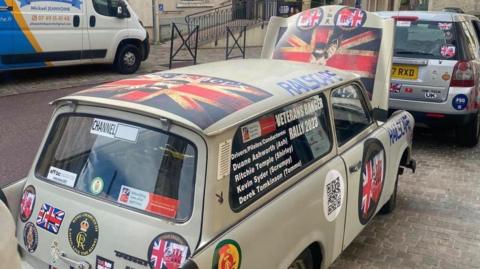 Green-coloured Trabant with team names in the window